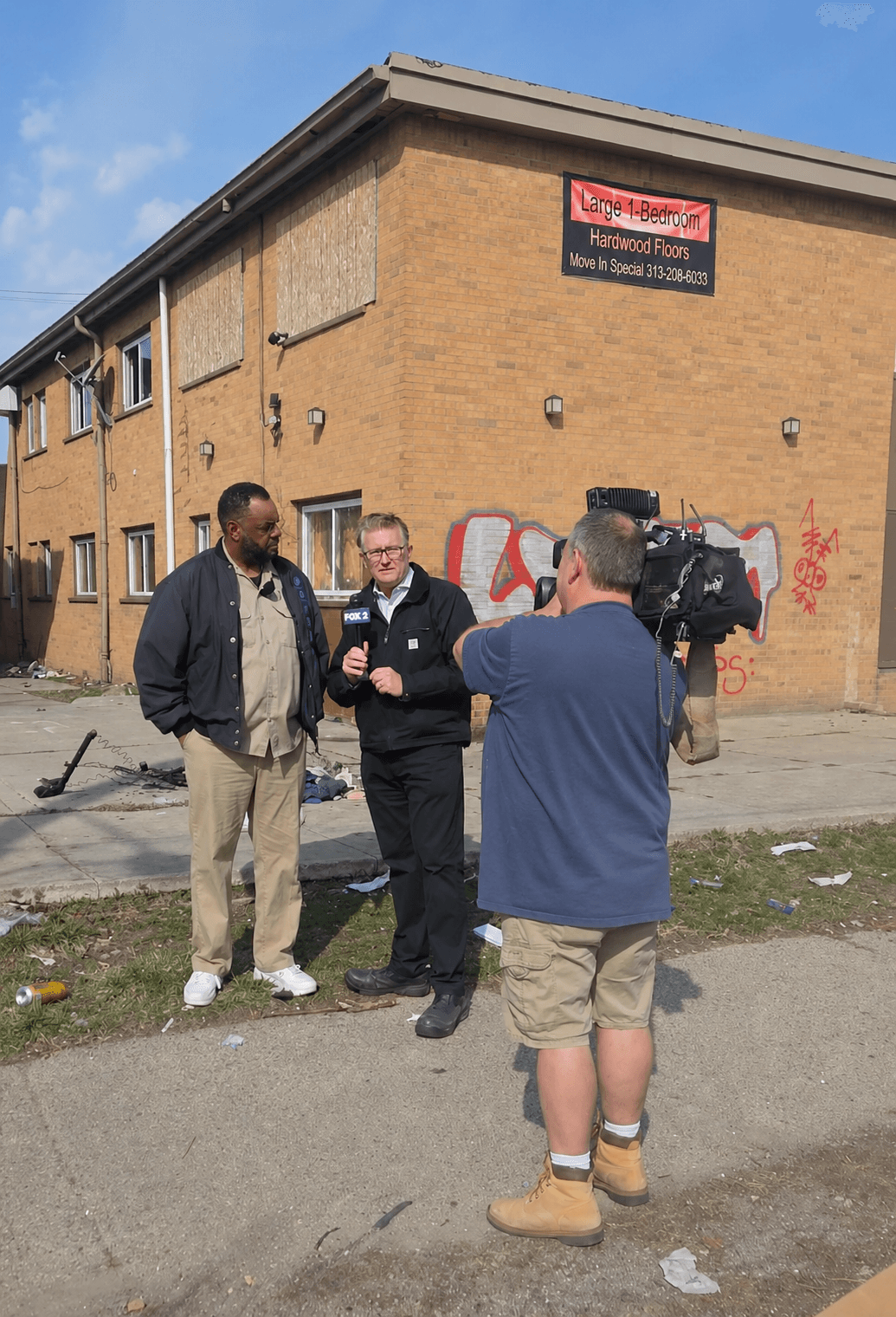 Michael A. Evans being interviewed by Fox 2 News in front of a blighted, boarded-up apartment building in Wayne County.